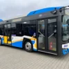 Miejski autobus stojący na placu przed budynkiem.