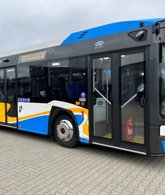 Miejski autobus stojący na placu przed budynkiem.