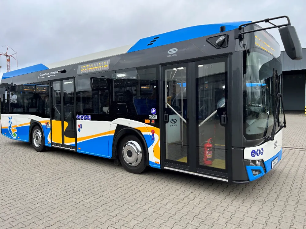 Miejski autobus stojący na placu przed budynkiem.